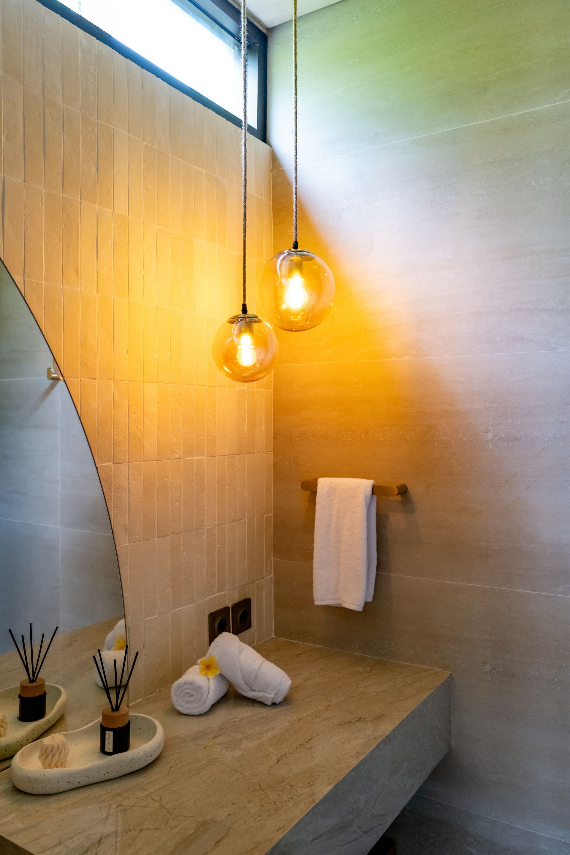 Bathroom with a stone countertop, a large mirror, two hanging globe lights, and a towel rack with a white towel.