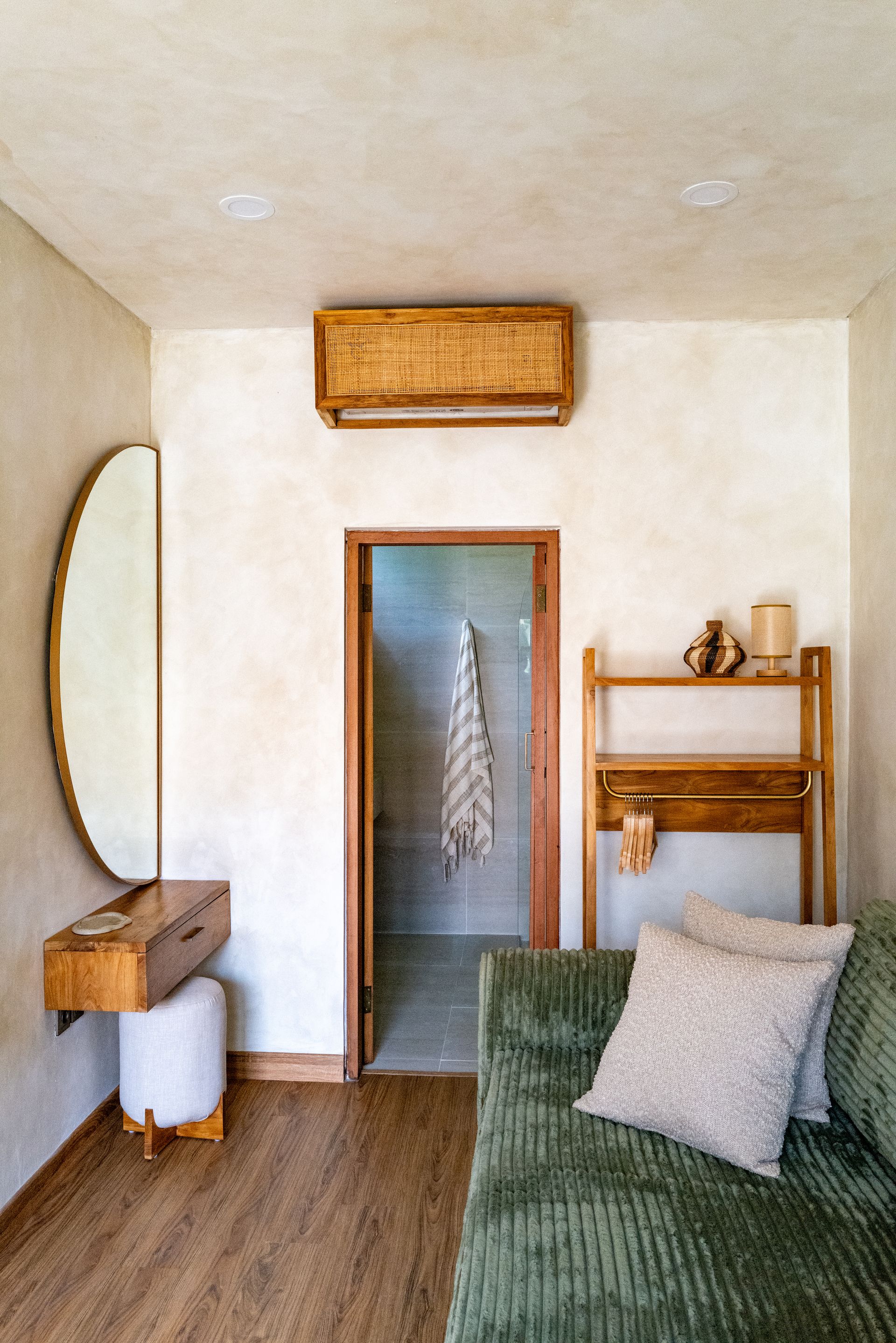 Cozy room with olive green sofa, wooden furniture, and doorway leading to a shower.