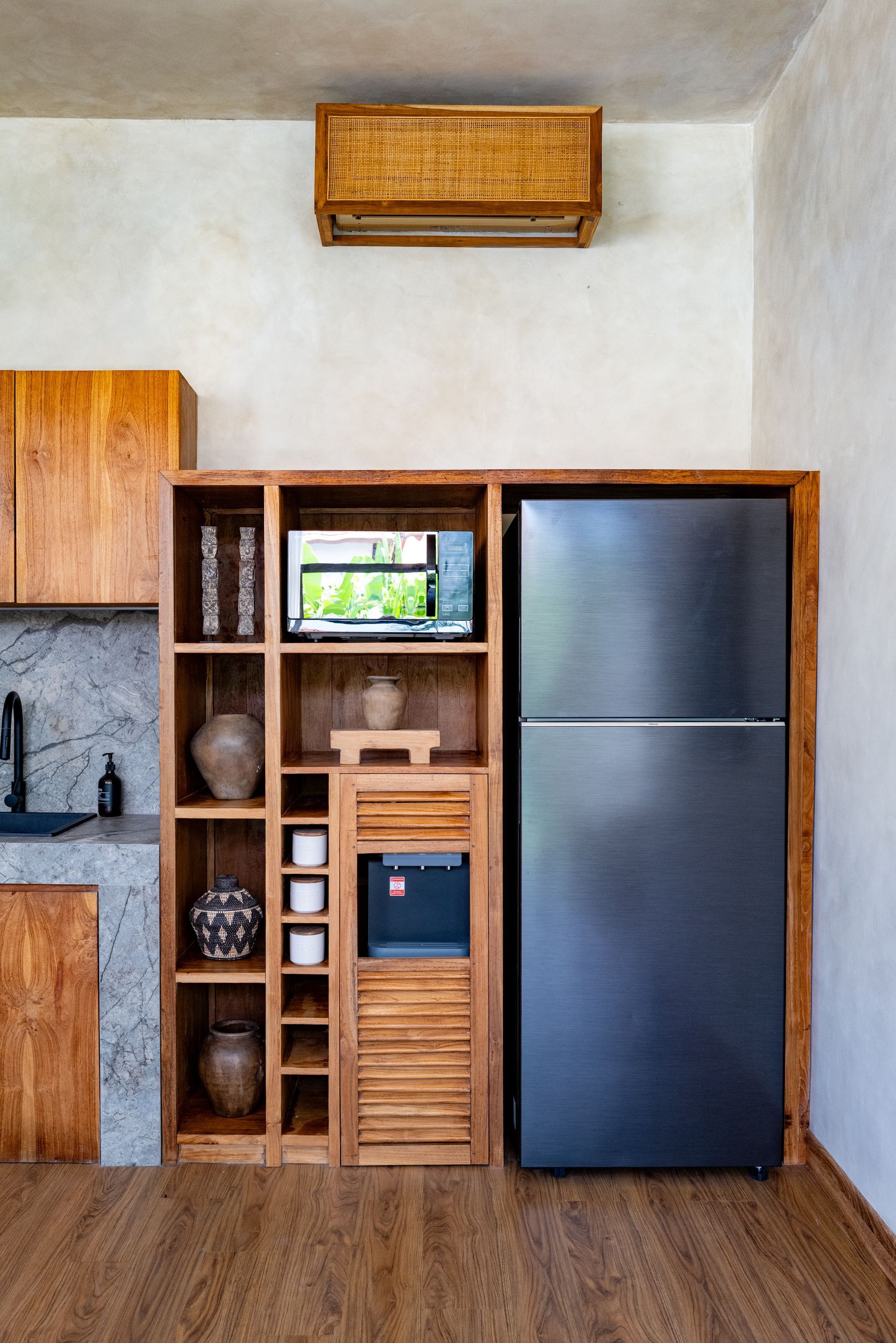 Wooden kitchen shelving with built-in microwave, refrigerator, and water dispenser.