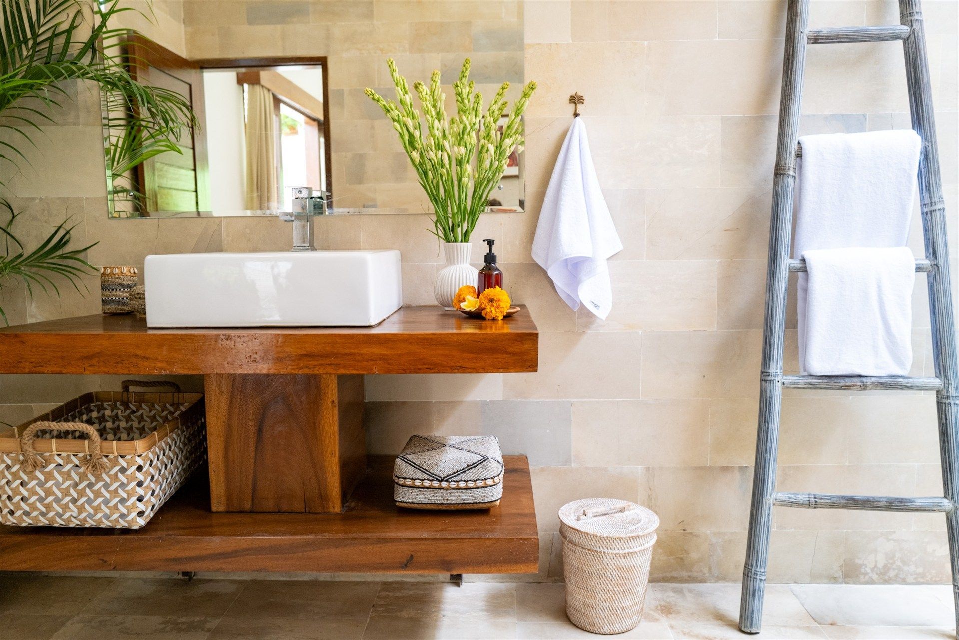 Bathroom with wooden vanity, white sink, and decorative elements.  A ladder holds towels.