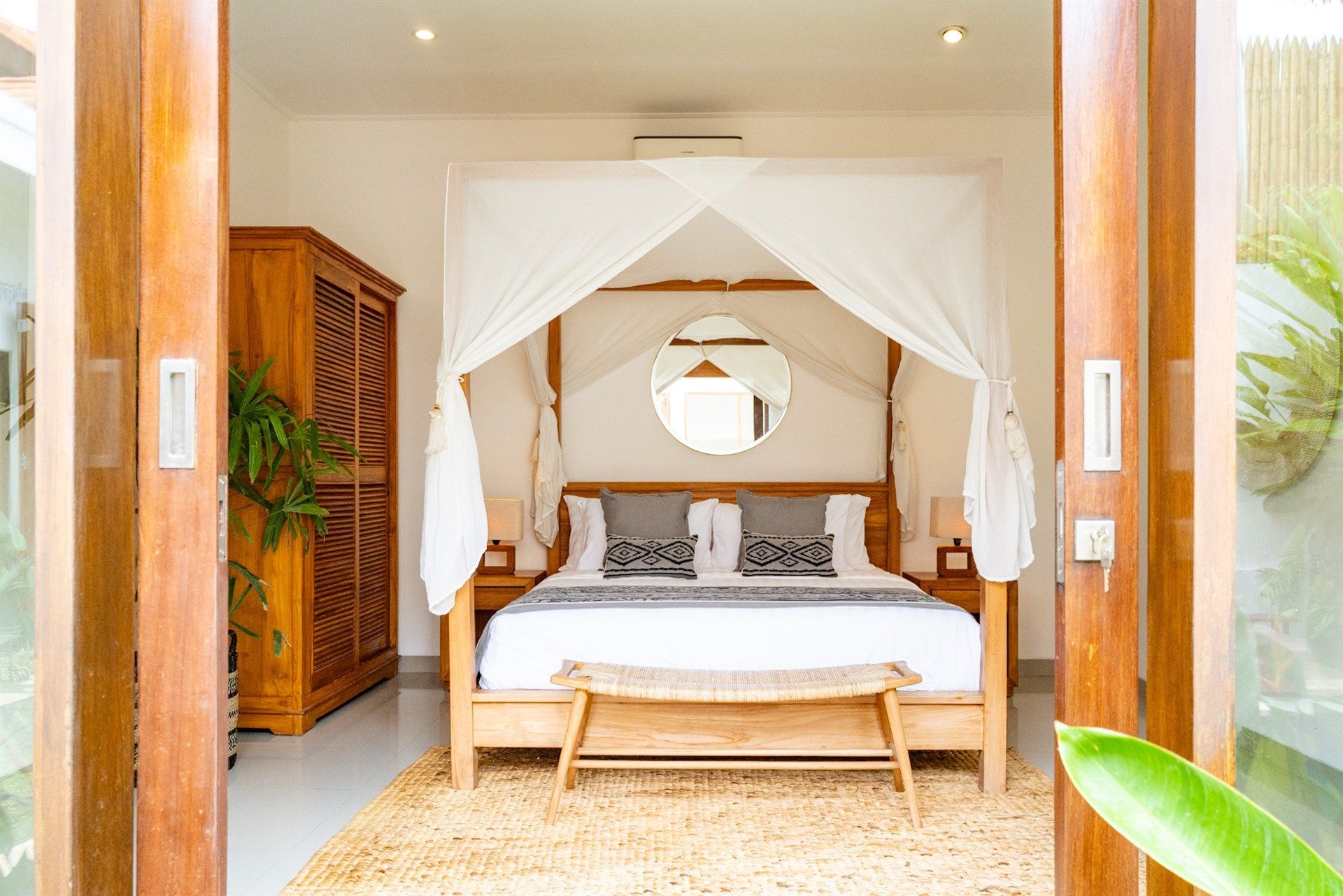 Bedroom with canopy bed, wooden furniture, and neutral decor.