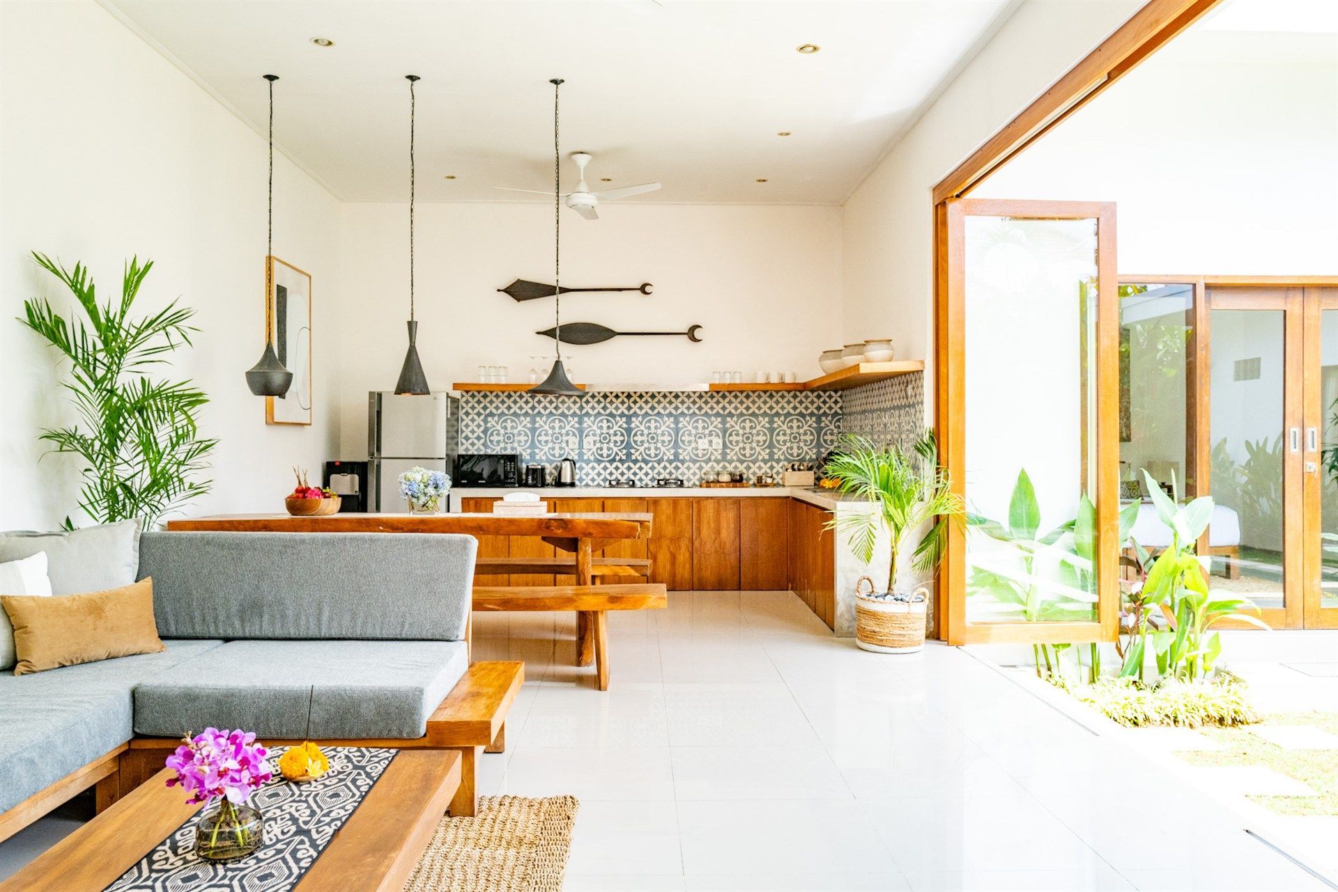 Open-plan kitchen and living area with wooden furniture, plants, and an outdoor view.