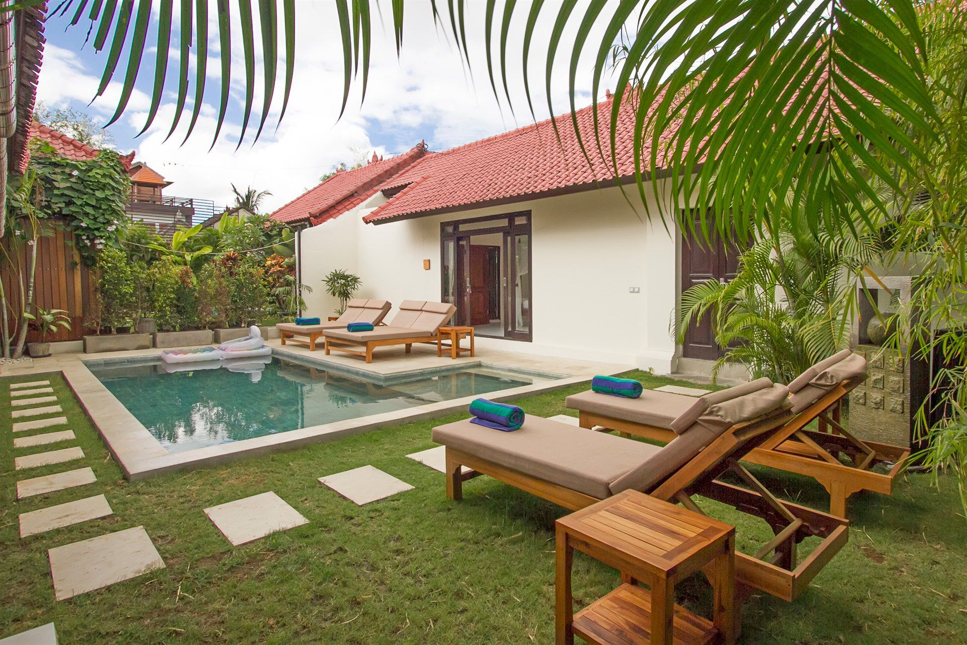 Backyard villa with a pool, lounge chairs, and green lawn.