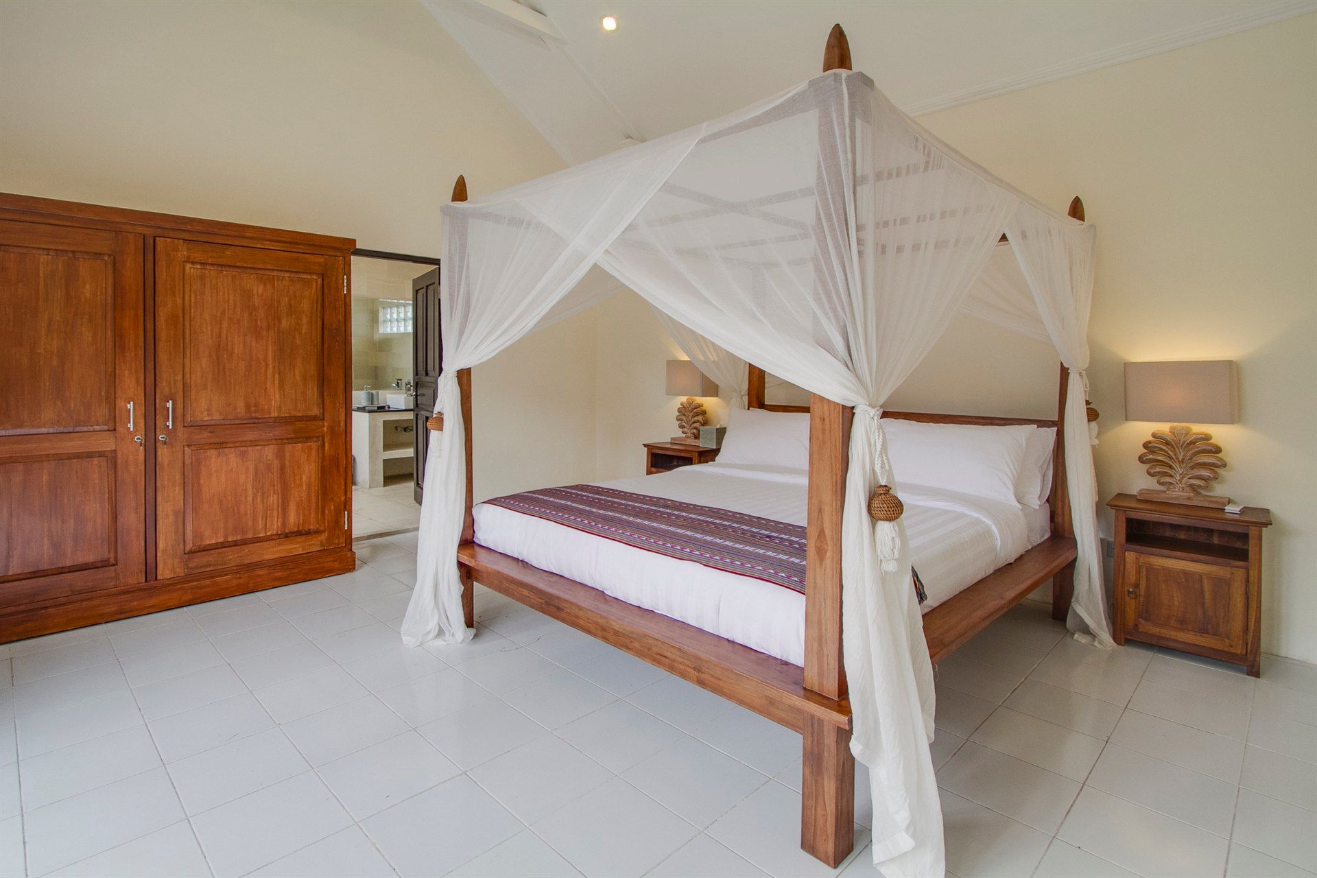 A bedroom with a four poster bed and a mosquito net.
