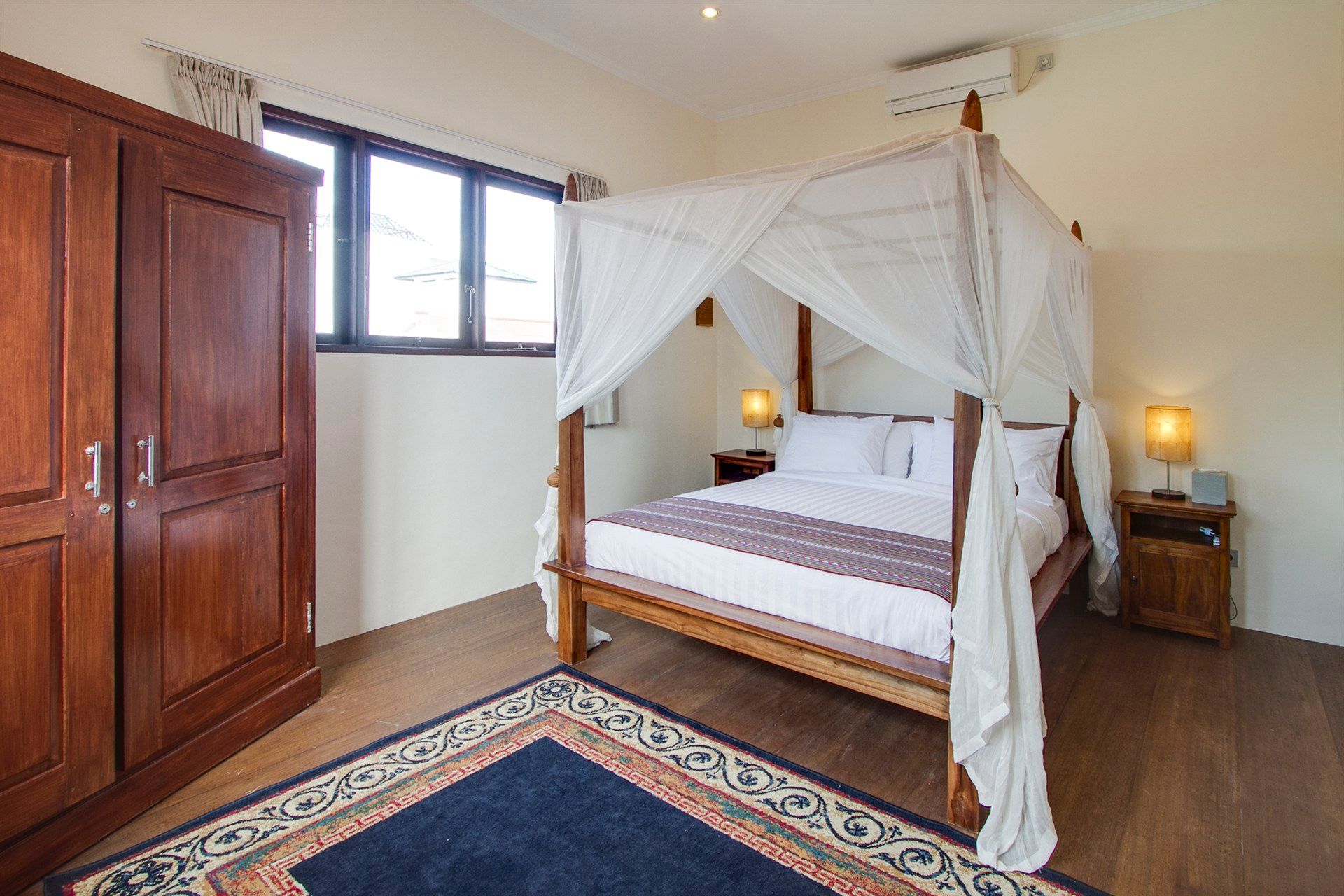 A bedroom with a canopy bed and a rug.