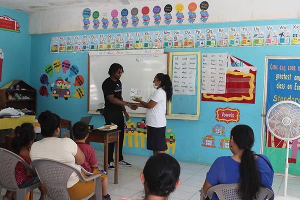 Student receiving an award from a local school teacher in Belize