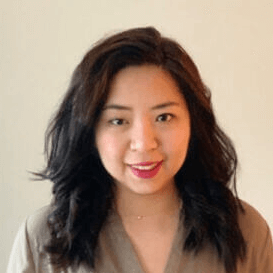 Woman with dark hair smiles, wearing a neutral-colored top.
