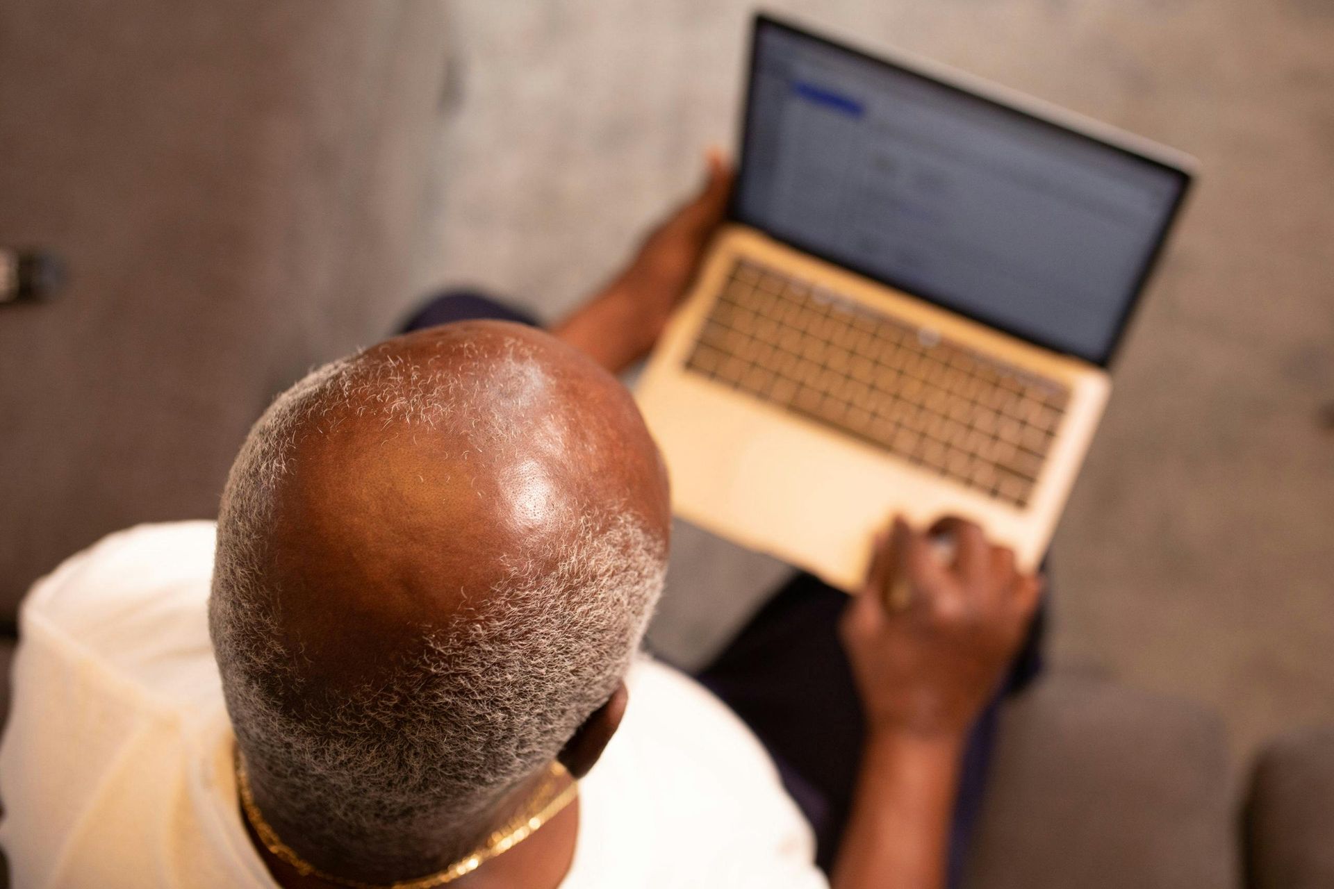 Overhead view of a person using a laptop, hands on keyboard and touchpad.