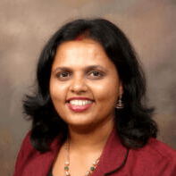 Woman with dark hair smiling, wearing a burgundy blazer and earrings.