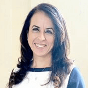 Woman with dark hair smiling, wearing a blue and white top.