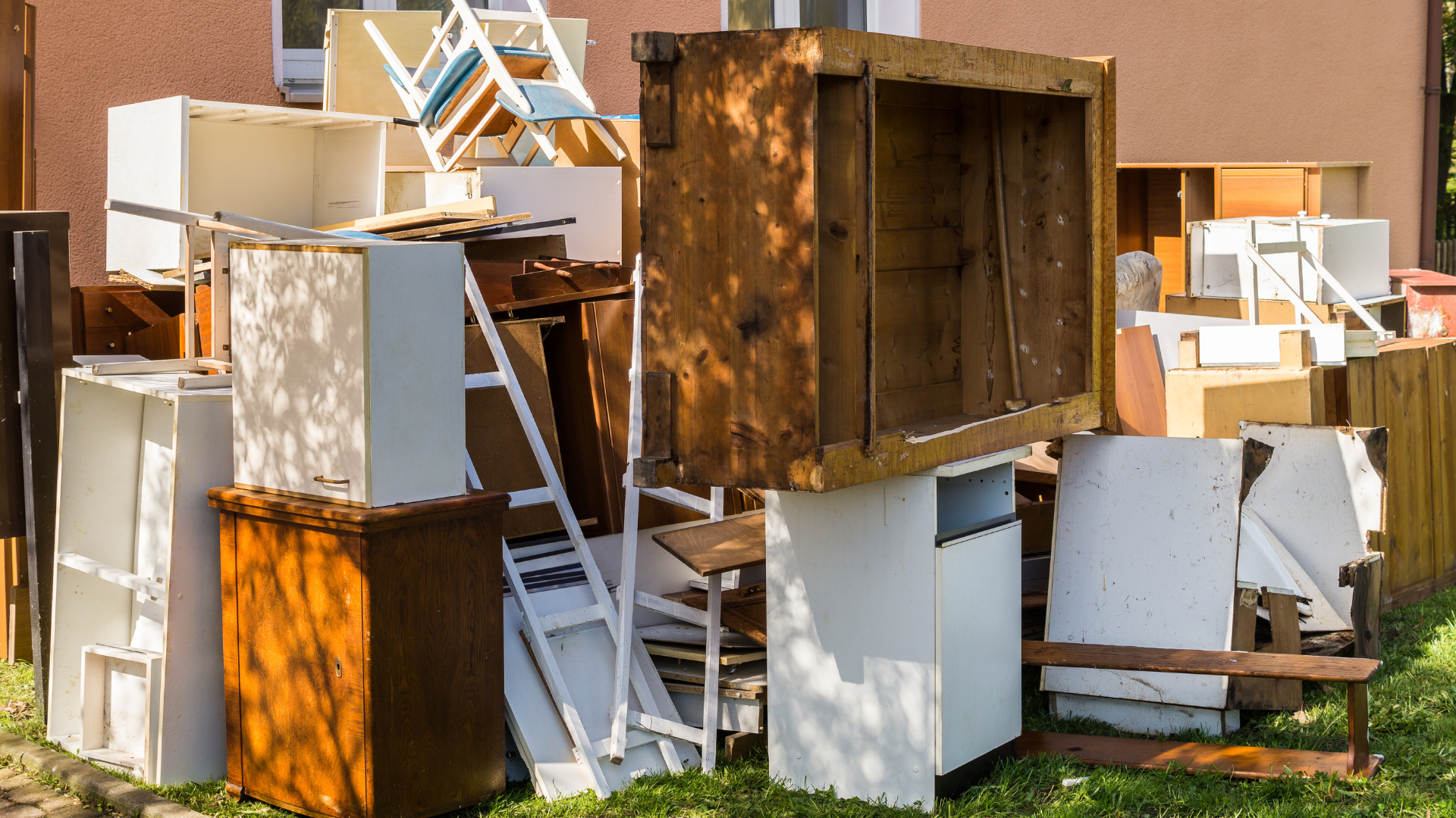 A pile of junk is sitting in the grass in front of a building.