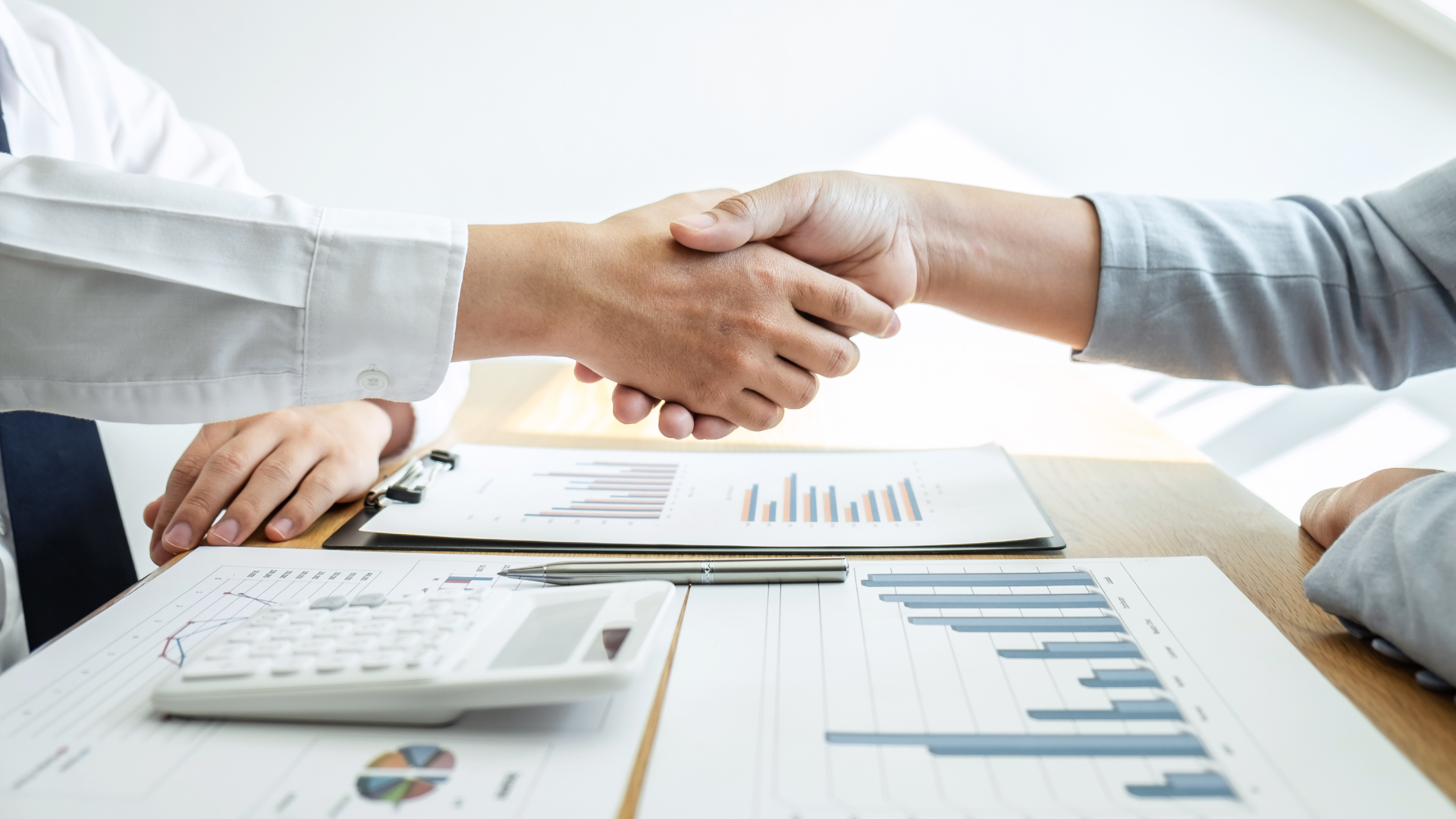 A man and a woman are shaking hands over a table.