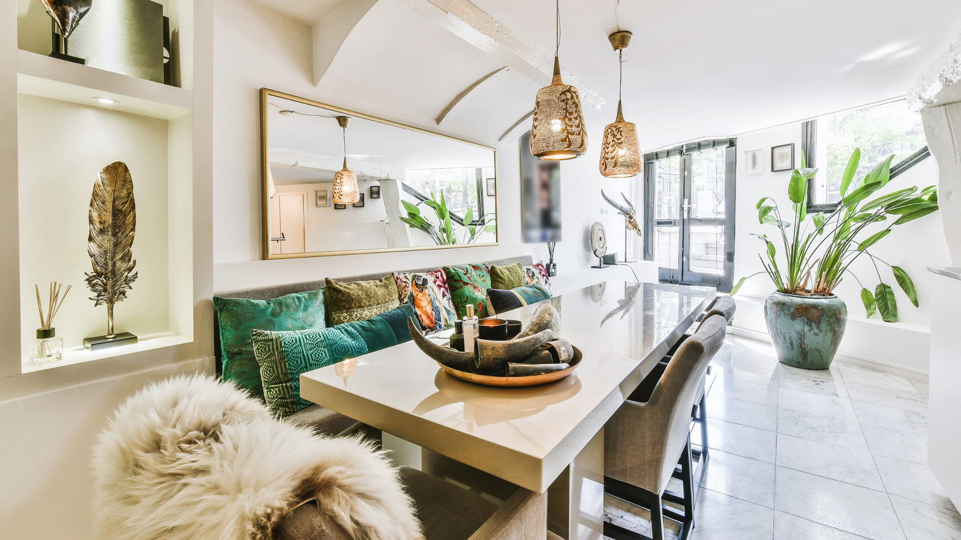 A dining room with a table and chairs and a large mirror on the wall.