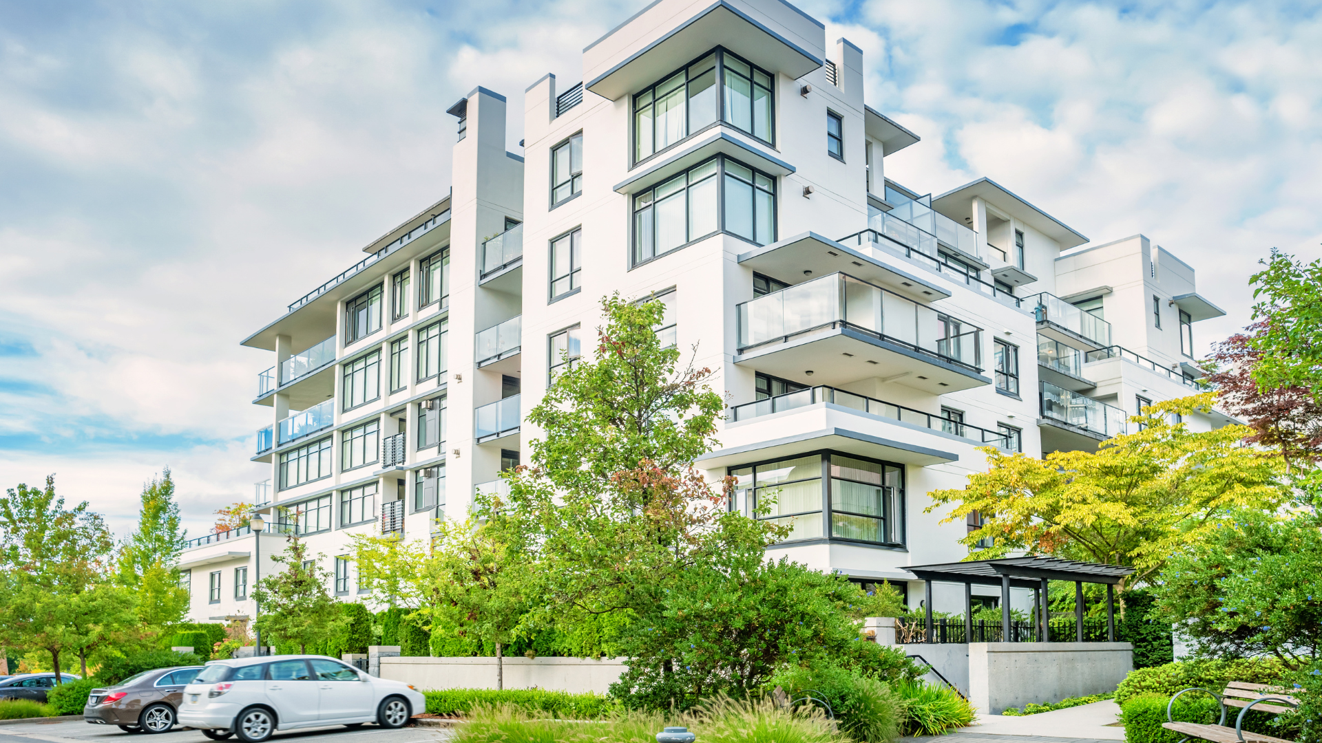 A large white apartment building with cars parked in front of it.