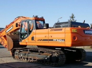 An orange doosan excavator is parked on the side of the road