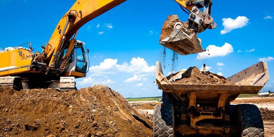 A yellow excavator is loading dirt into a dump truck.