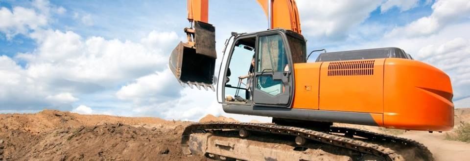 A large orange excavator is digging a hole in the dirt.