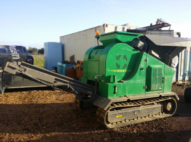 A green machine is parked in a dirt field