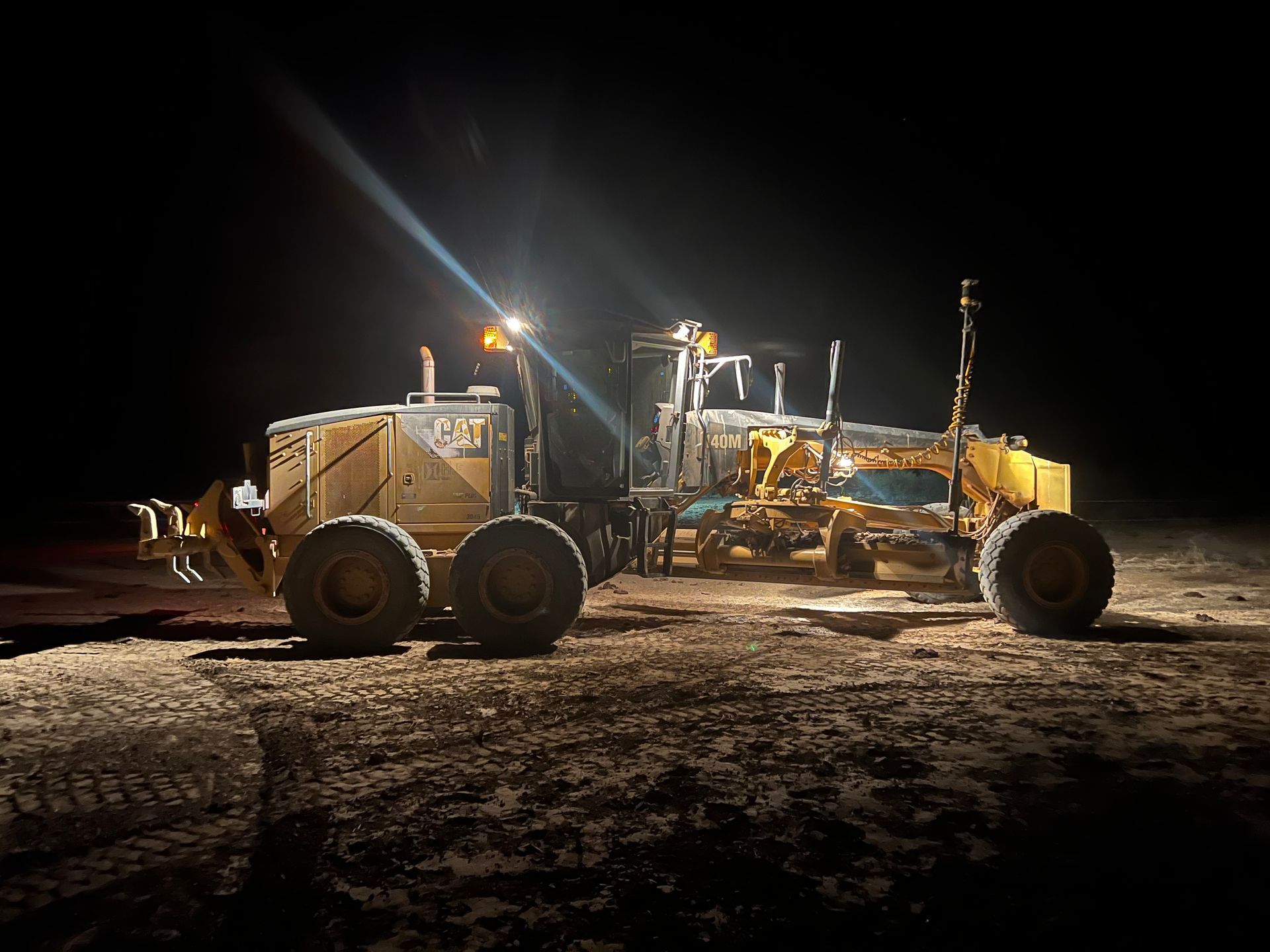A bulldozer is parked in a dirt field at night.