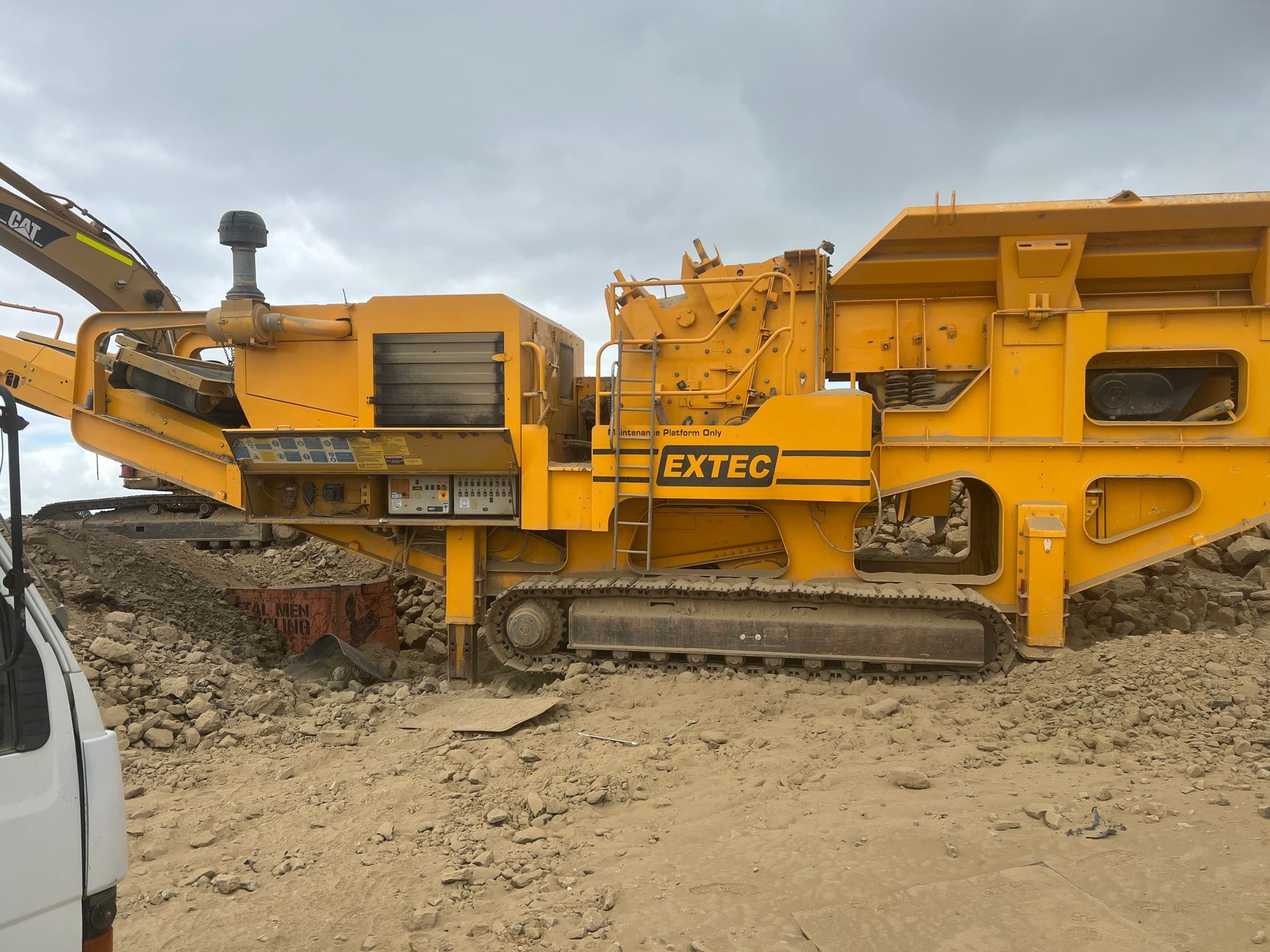 A large yellow machine is sitting in the middle of a dirt field.
