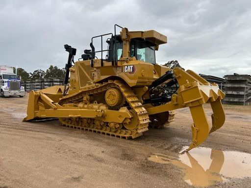 A large yellow bulldozer is parked in a dirt field.