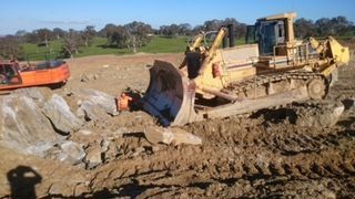 A bulldozer is driving through a muddy field.