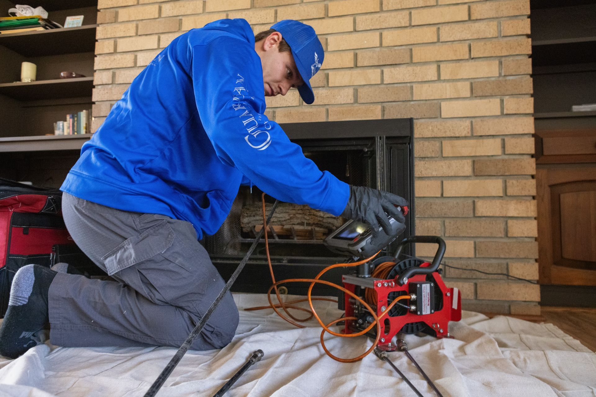 A man wearing a hard hat and safety vest is working on a fireplace.