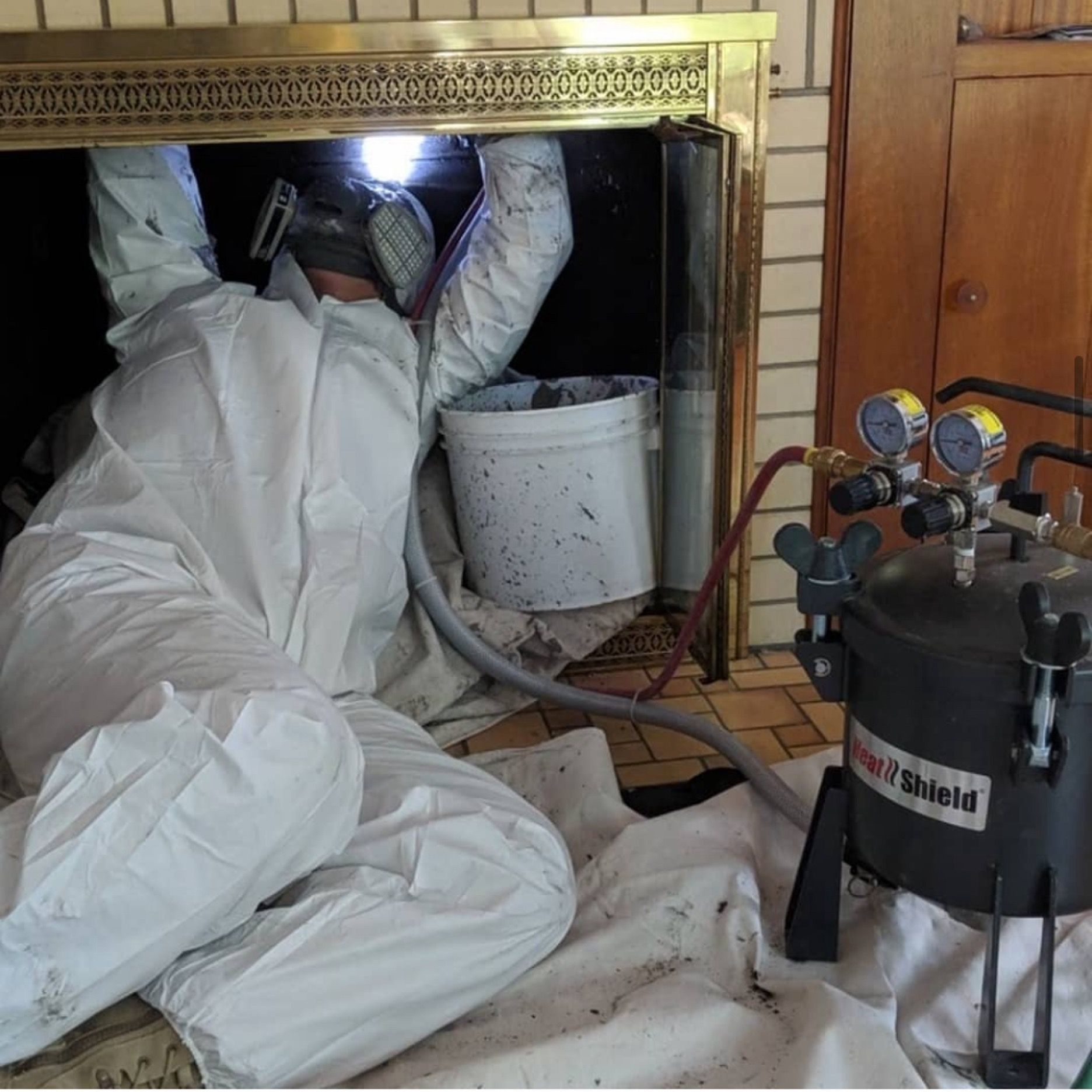 A man in a white suit is working on a fireplace