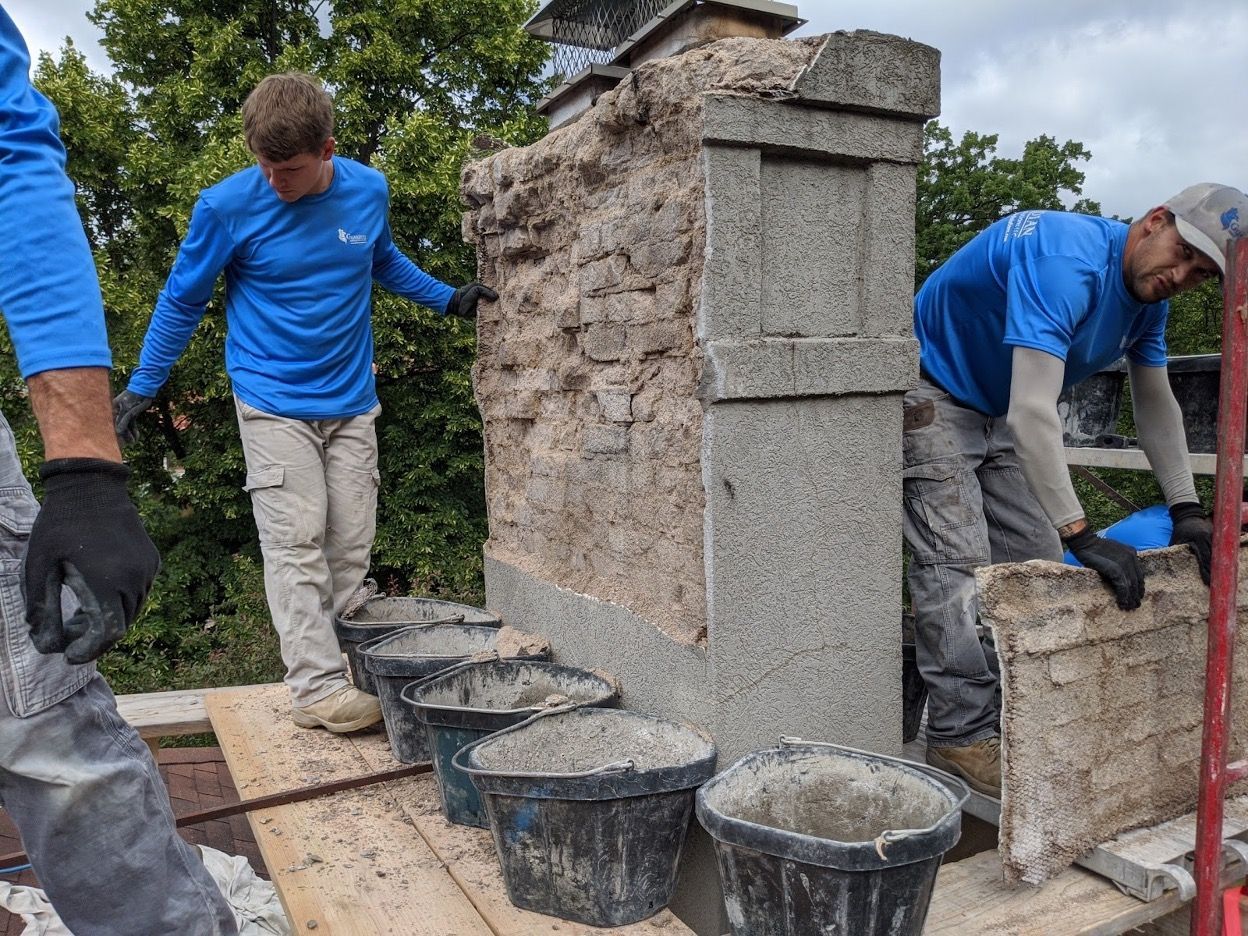 A group of construction workers are working on a chimney.