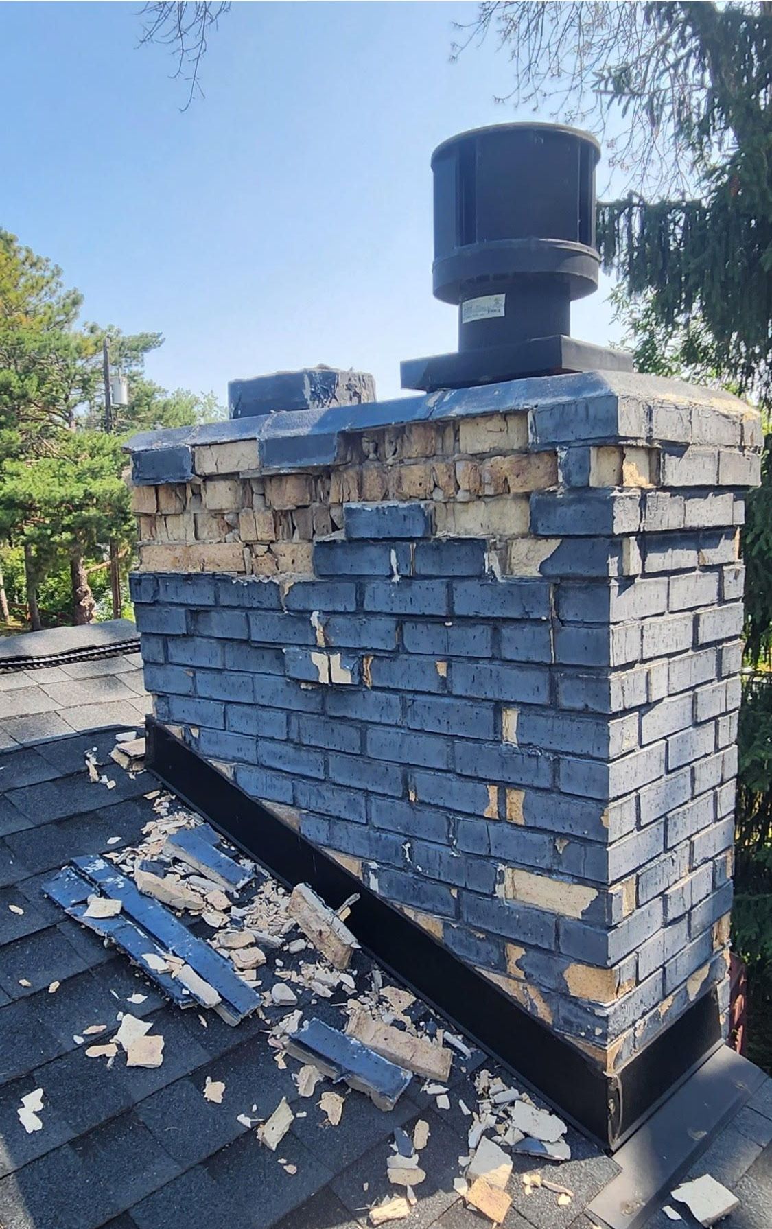A brick chimney is sitting on top of a roof.