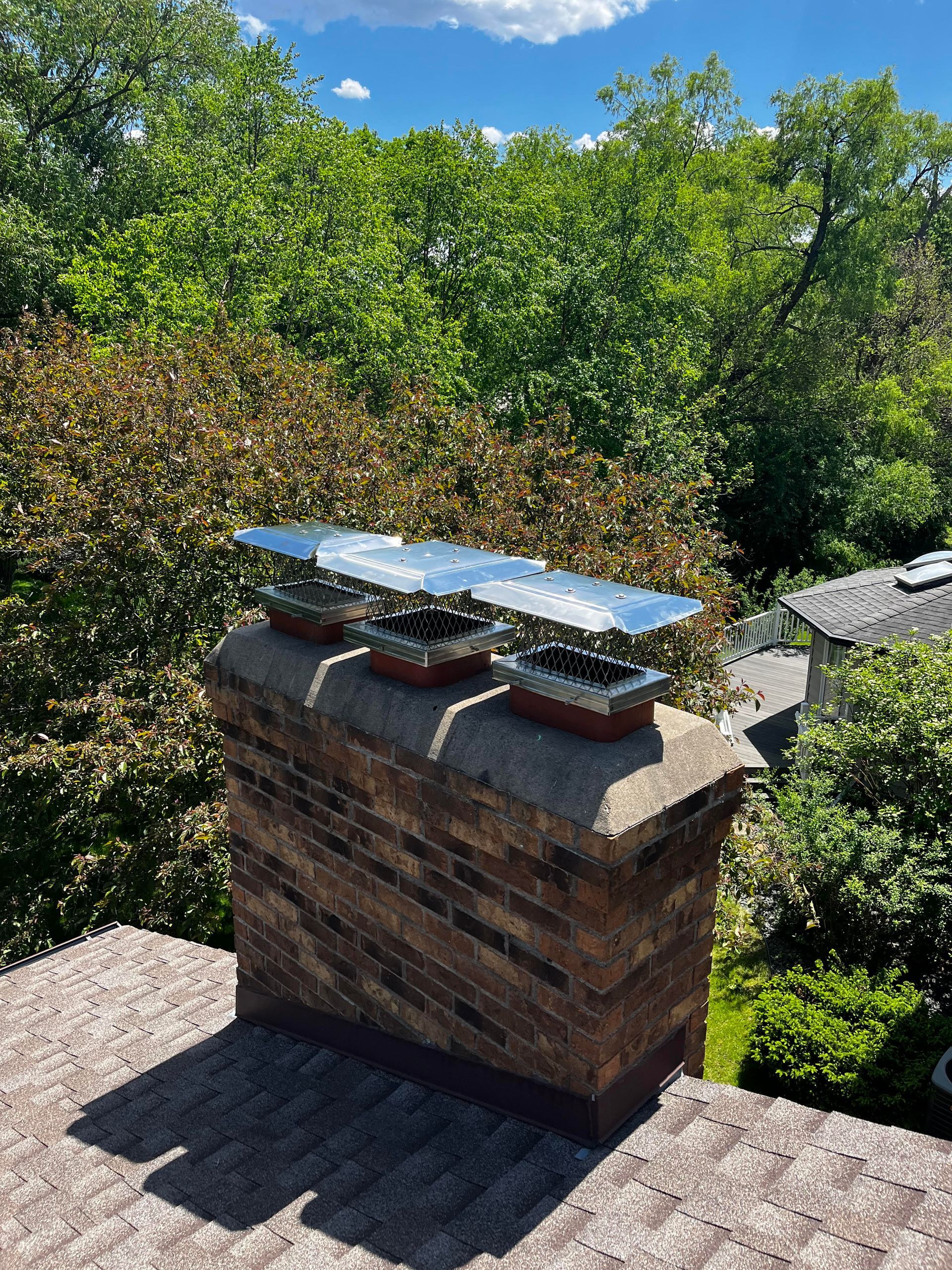 A chimney on top of a roof with trees in the background.