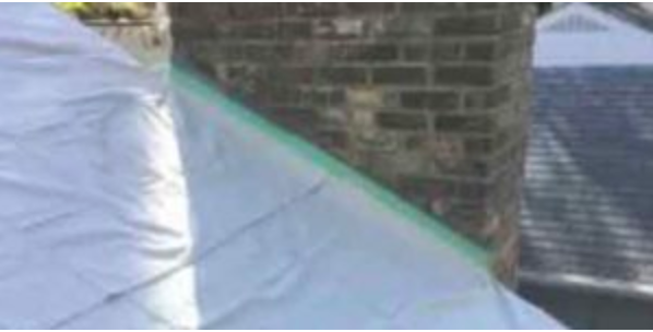 A brick chimney is being painted with a green tape.