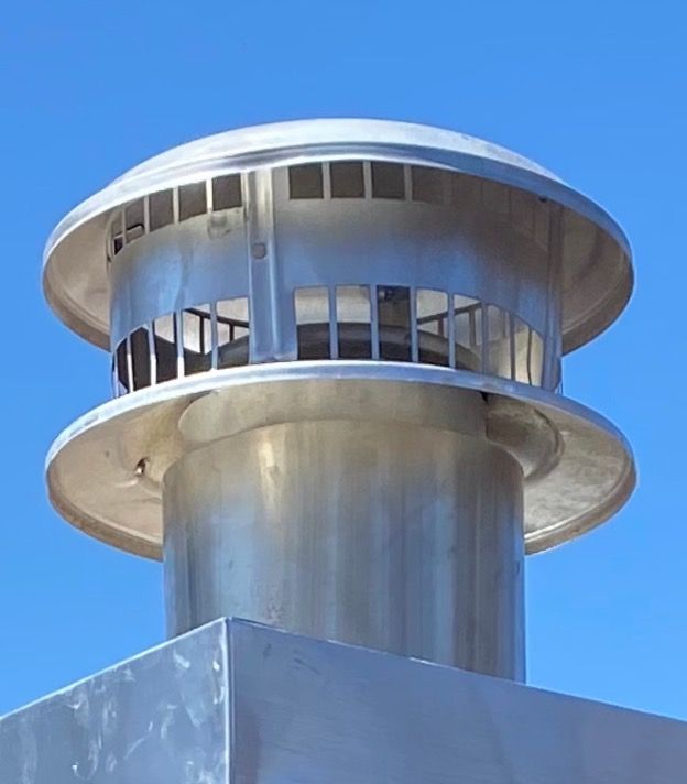 A stainless steel chimney with a blue sky in the background