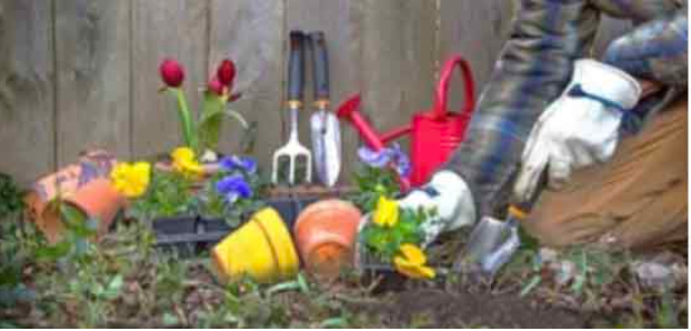 A person is planting flowers in a garden with gardening tools