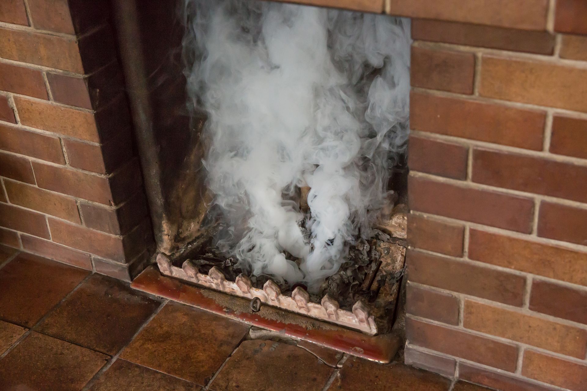 A brick fireplace with smoke coming out of it