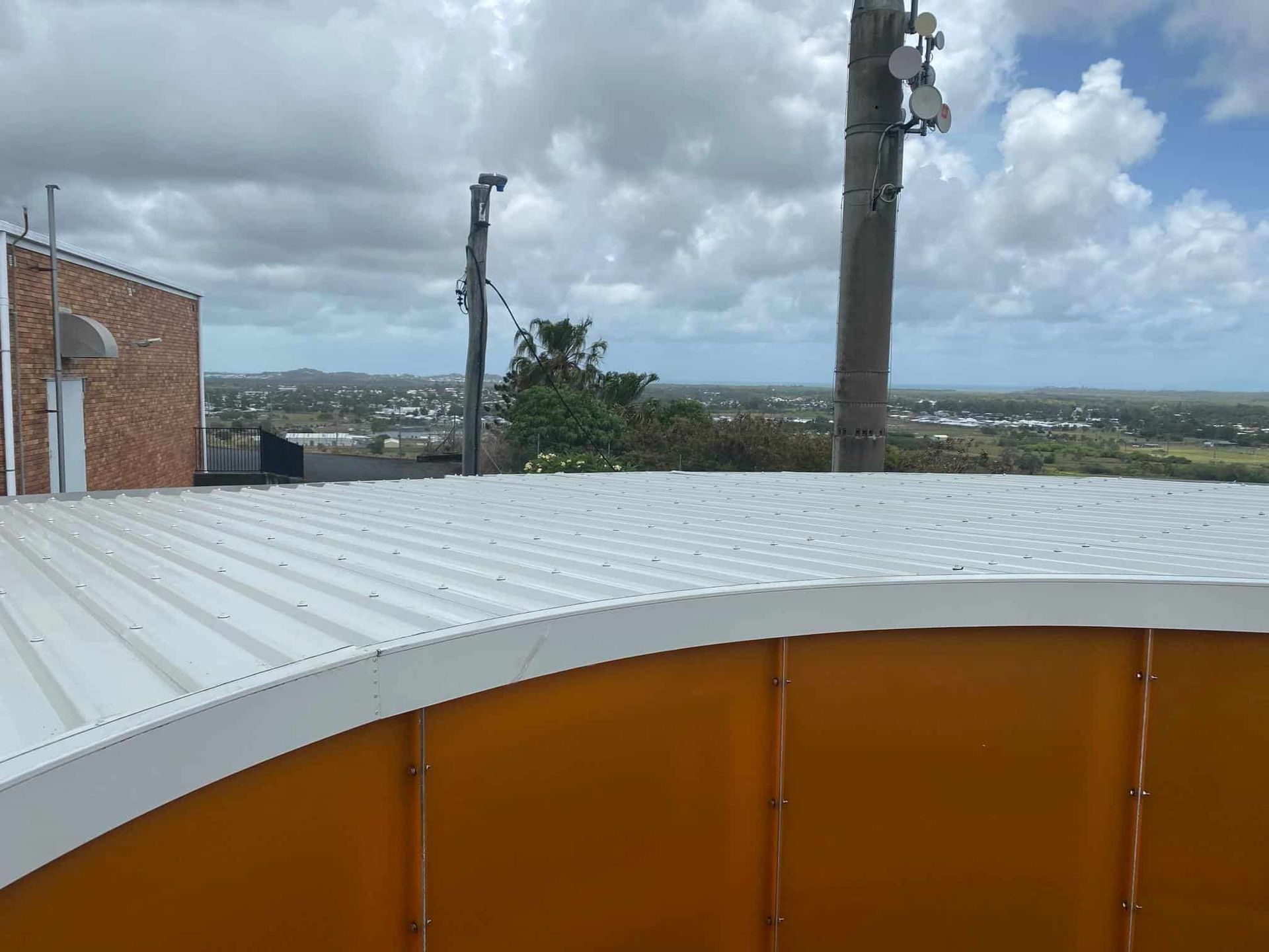 A White Roof With a View of a City and a Palm Tree — Reed Plumbing Industries in Mackay, QLD