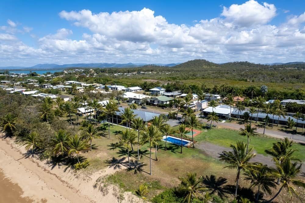 An Aerial View of a Beach With Palm Trees and Houses — Reed Plumbing Industries in Sarina, QLD