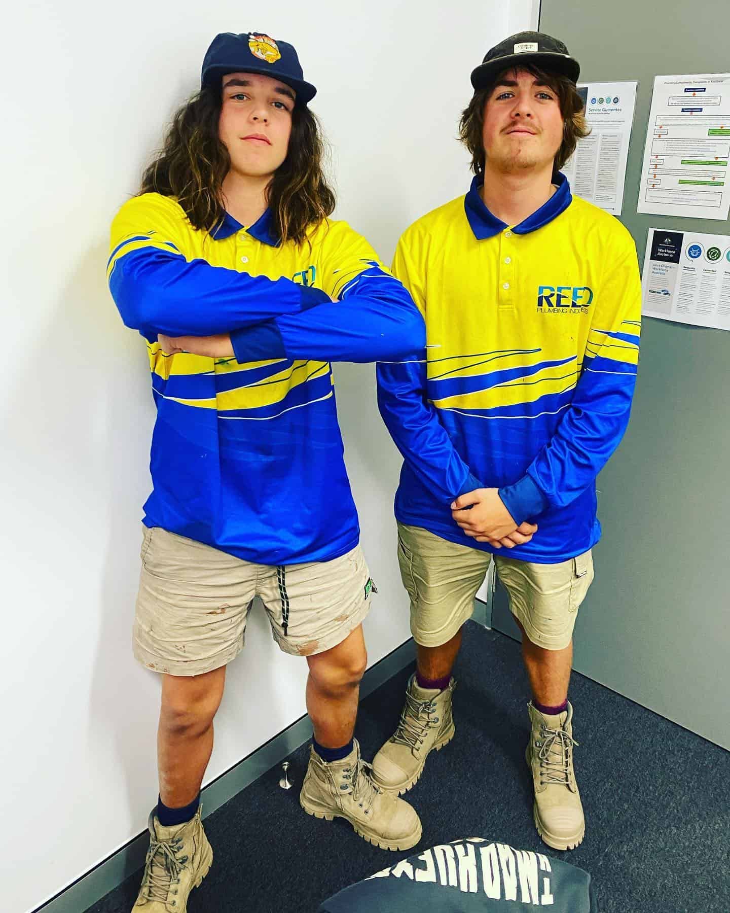 Two Men Wearing Blue and Yellow Shirts Are Standing Next to Each Other With Their Arms Crossed — Reed Plumbing Industries in Mackay, QLD