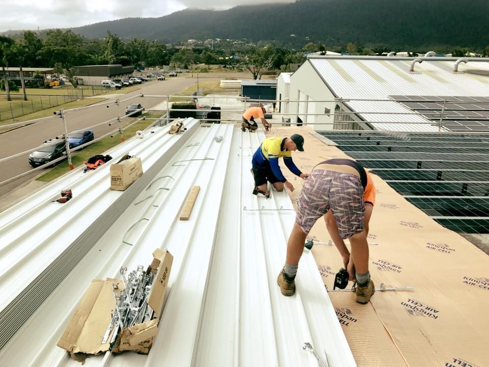 A Group of People Are Working on the Roof of a Building — Reed Plumbing Industries in Proserpine, QLD