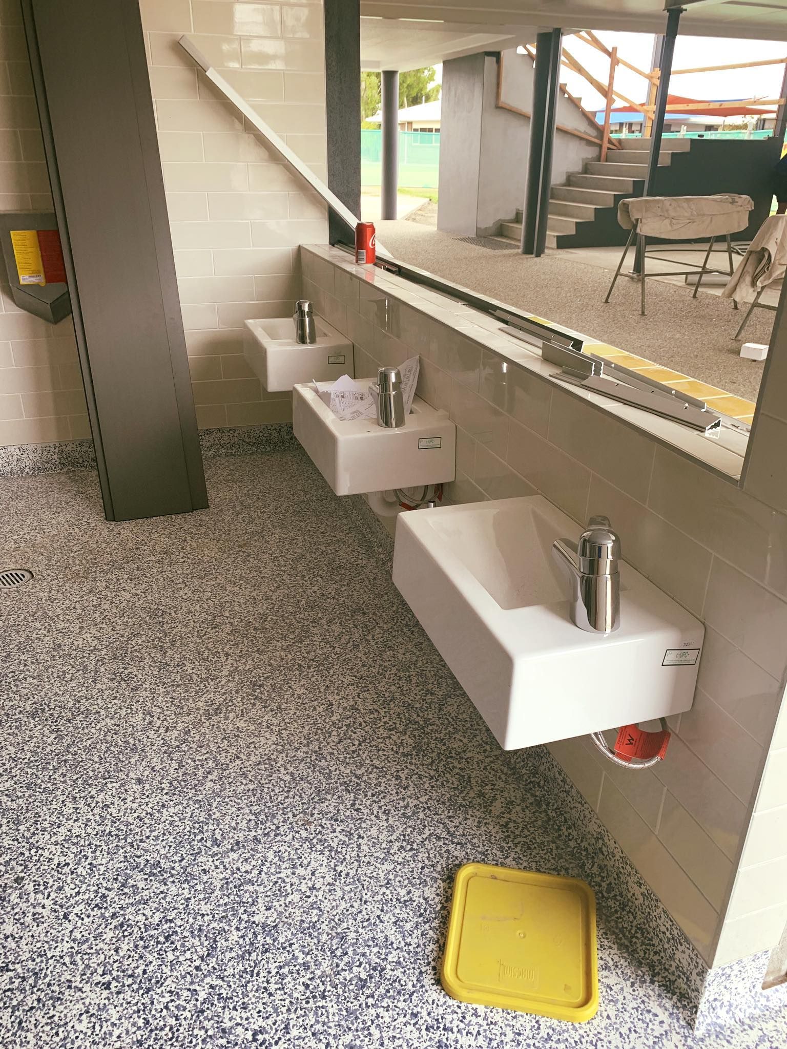A bathroom with three sinks and a yellow trash can on the floor — Reed Plumbing Industries in Mackay, QLD