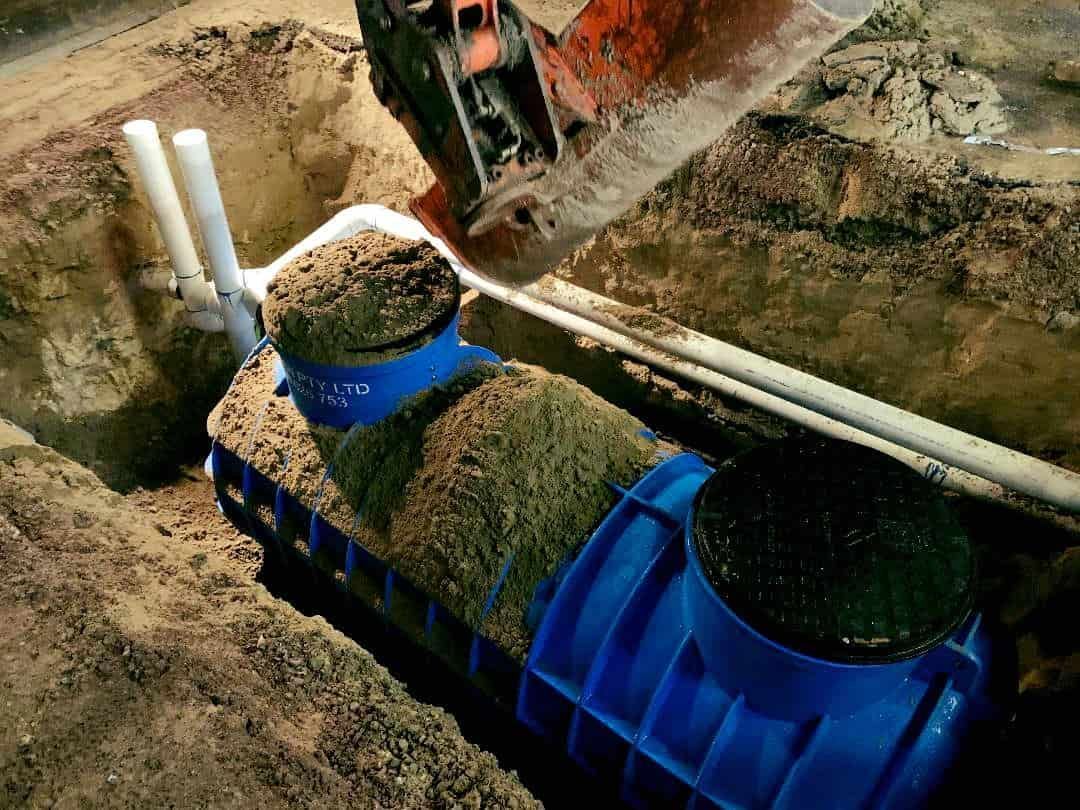 A Blue Septic Tank is Being Installed in a Hole in the Ground — Reed Plumbing Industries in Mackay, QLD