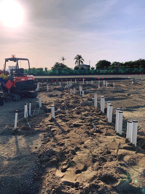 A Construction Site With a Lot of White Pipes in the Dirt — Reed Plumbing Industries in Mackay, QLD
