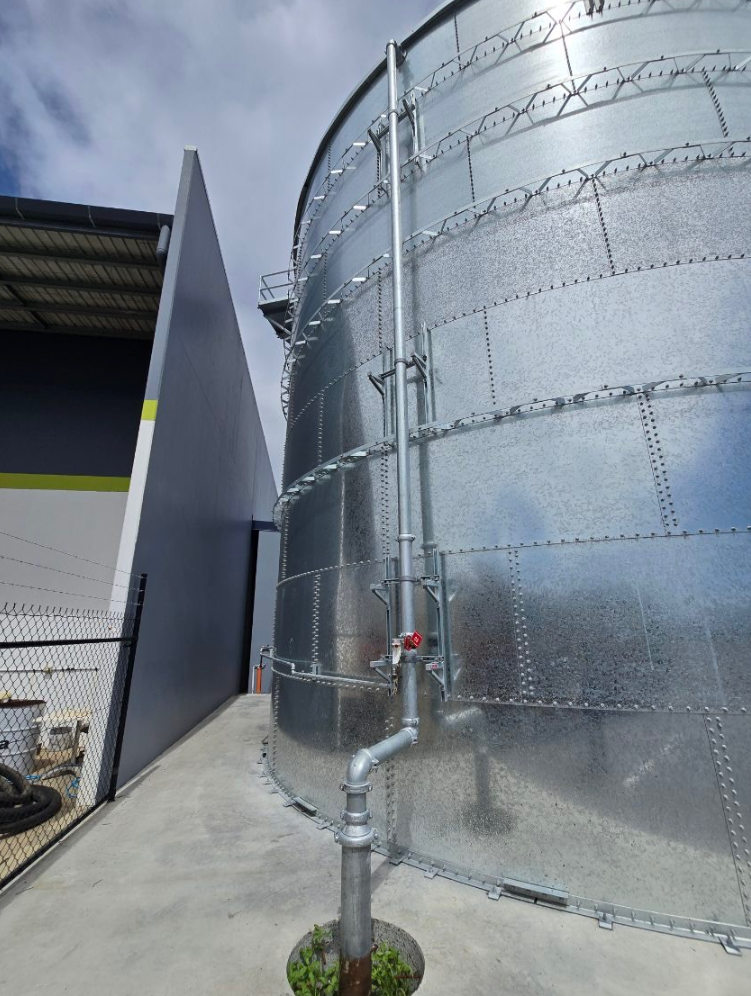 A Manhole Cover is Being Installed on the Sidewalk in Front of a Building — Reed Plumbing Industries in Mackay, QLD