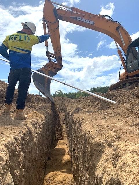 Three People with Their Backs to the Camera with Yellow Branded Shirts saying Reed Plumbing Industry - Reed Plumbing Industry Mackay