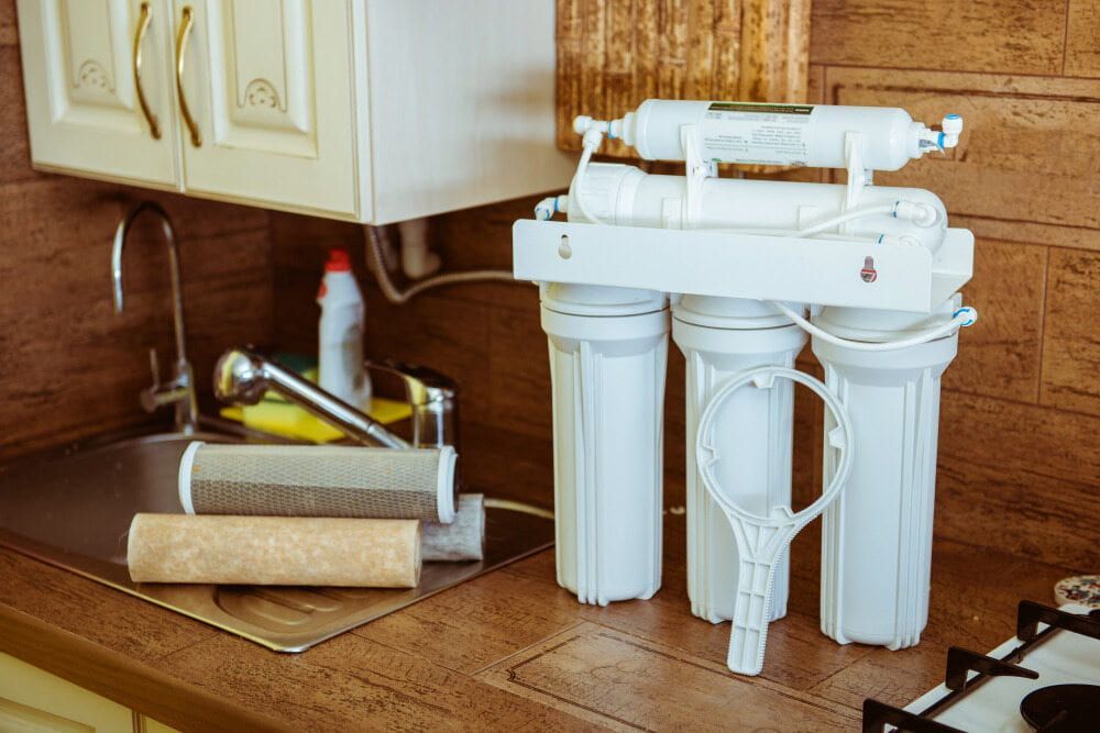A Water Filter is Sitting on a Kitchen Counter Next to a Sink — Reed Plumbing Industries in Mackay, QLD