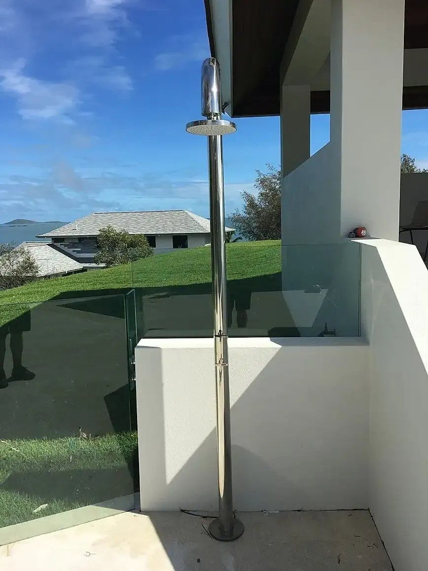 A Stainless Steel Outdoor Shower With a View of a House in the Background — Reed Plumbing Industries in Mackay, QLD