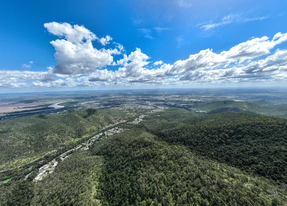 An Aerial View of a Lush Green Forest With a River Running Through It — Reed Plumbing Industries in Rockhampton, QLD