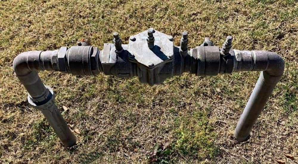 A Water Meter is Sitting on the Grass Next to a Pipe  — Reed Plumbing Industries in Mackay, QLD