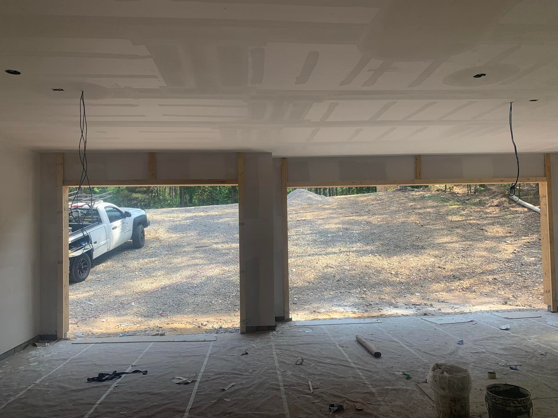 Interior view of a room with exposed doorways, drywall, and a view of a truck parked outside.