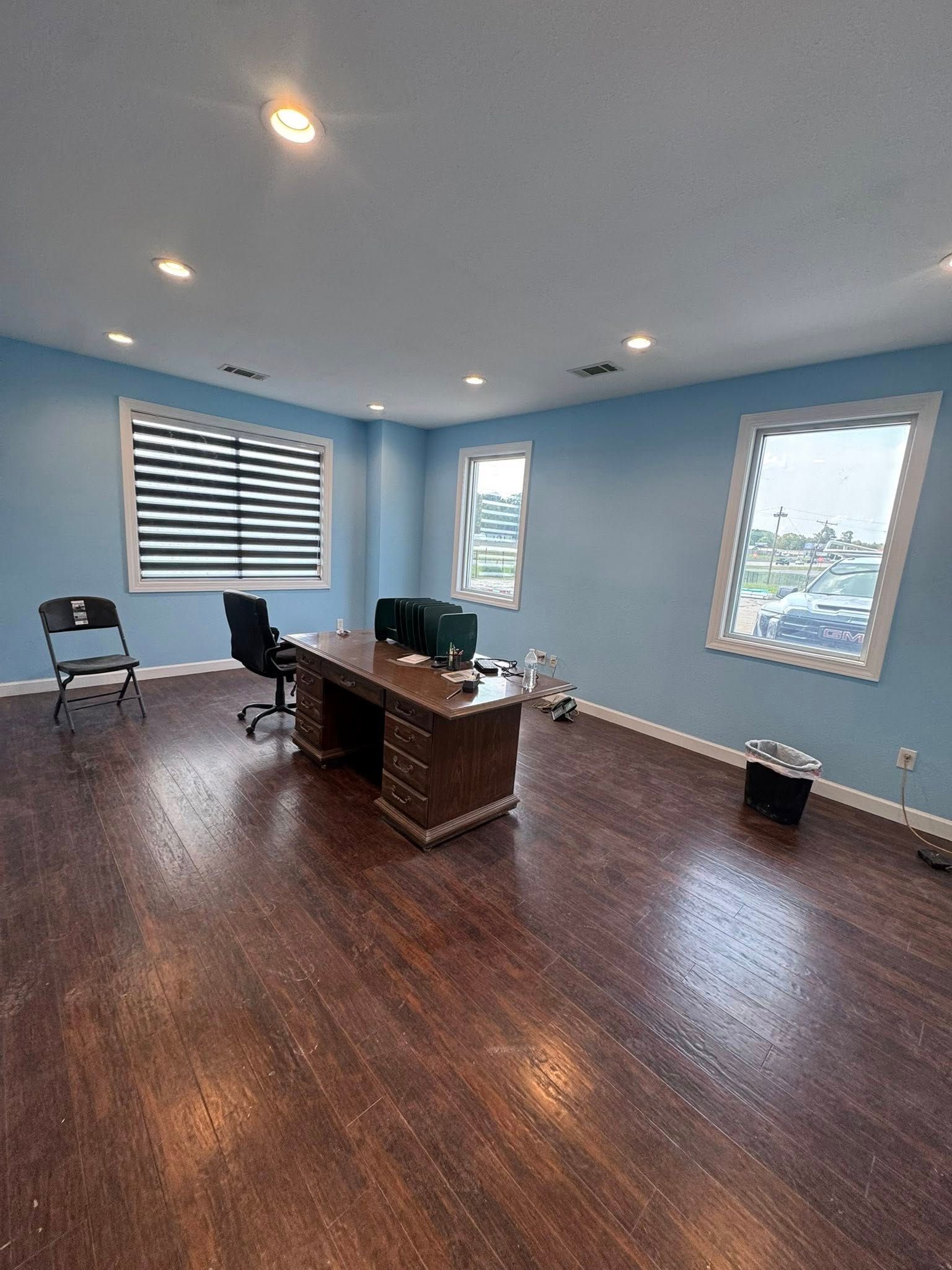Empty office with hardwood floors, blue walls, and a large desk.